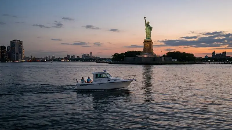 Boat capsized near Liberty Island context showing New York Harbor, the Statue of Liberty, and a recreational boat traveling normally.