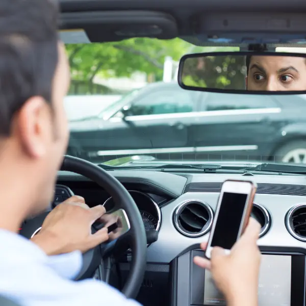 example of distracted driving in NYC, a driver texting while driving and about to collide with another vehicle