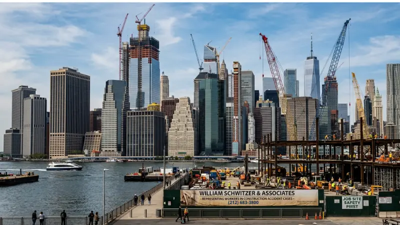 El perfil urbano de la ciudad de Nueva York con grúas que simbolizan los casos de accidentes laborales de William Schwitzer Construction y la defensa de los trabajadores lesionados.