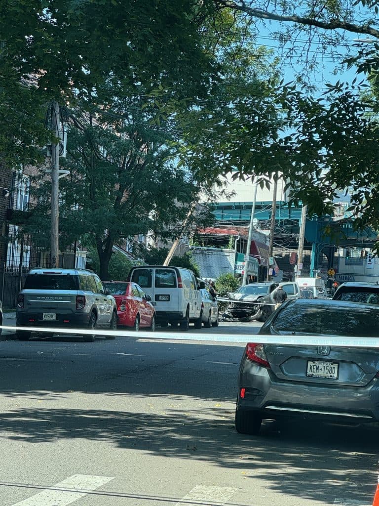 Escena de un accidente de tráfico en Nueva York con varios vehículos implicados, cinta amarilla de la policía bloqueando la carretera y coches dañados en un barrio de Brooklyn
