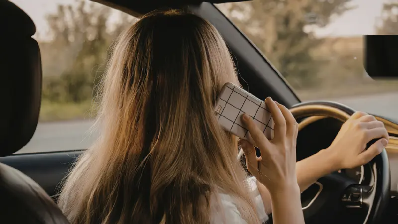 Conductor al volante con el móvil durante el Mes de la Concienciación sobre la Conducción Distraída