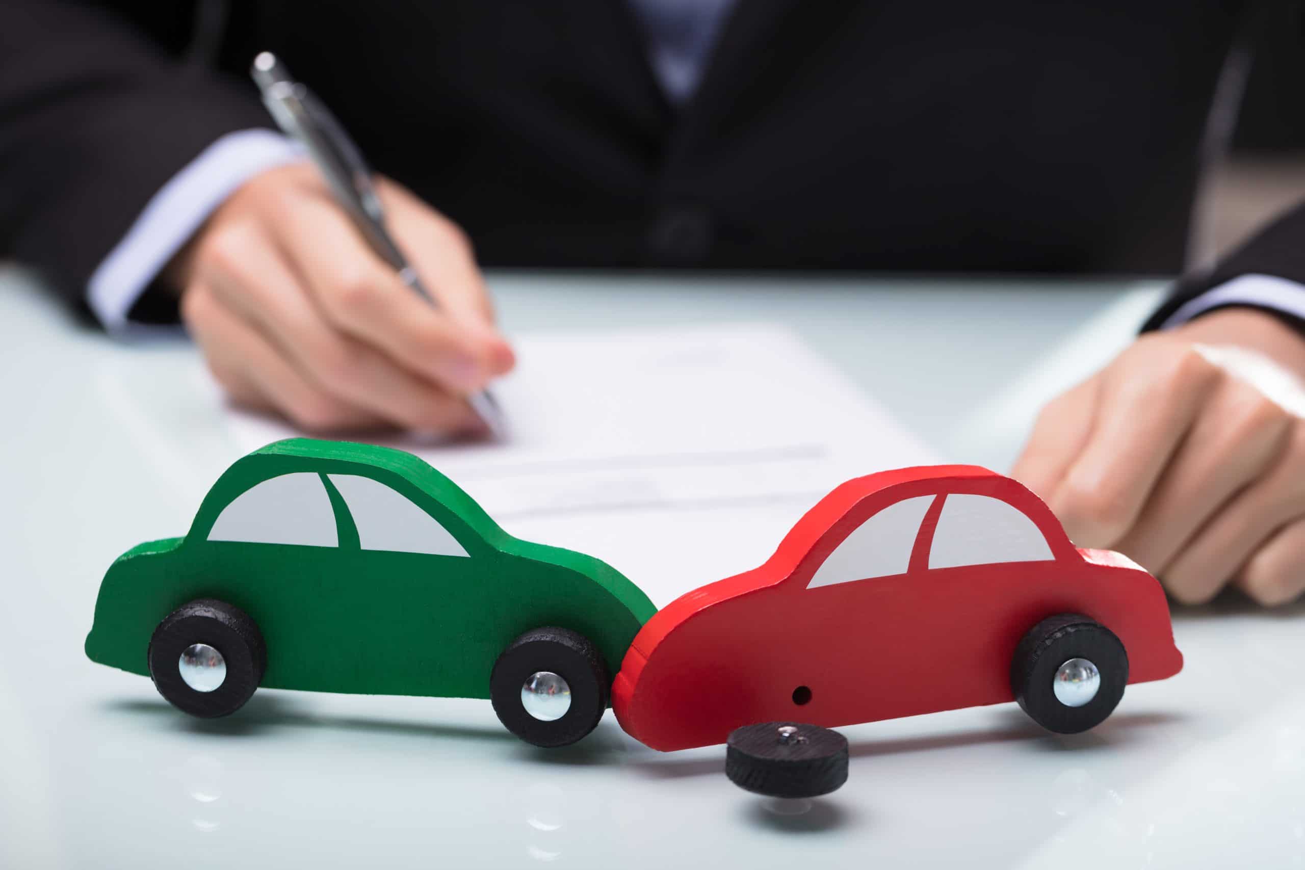 Close-up Of Red And Green Car In Front Of Businessman Writing On Paper