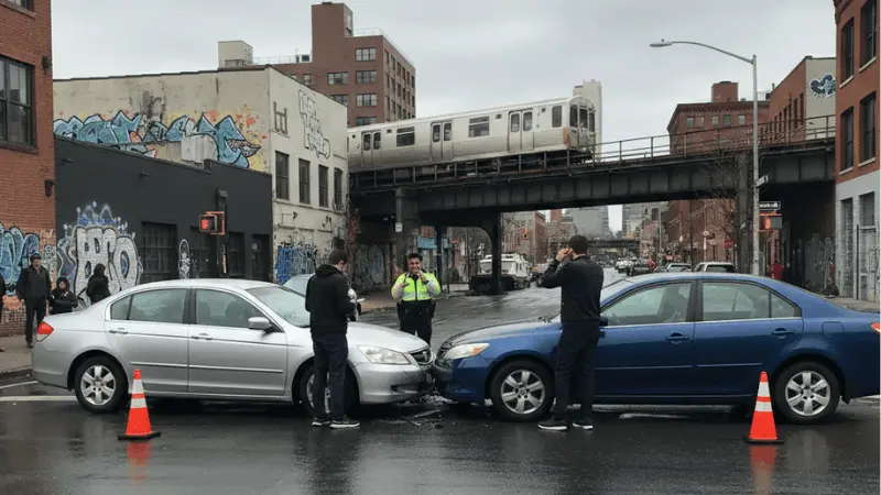 Head-on collision of two sedans under NYC elevated subway with police on scene and graffiti walls in background