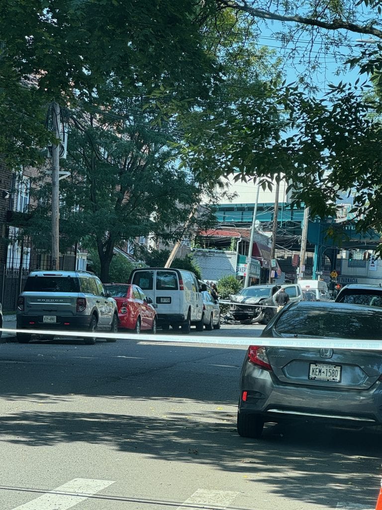 NYC car accident scene with multiple vehicles crashed, yellow police tape blocking the road, and damaged cars in Brooklyn neighborhood