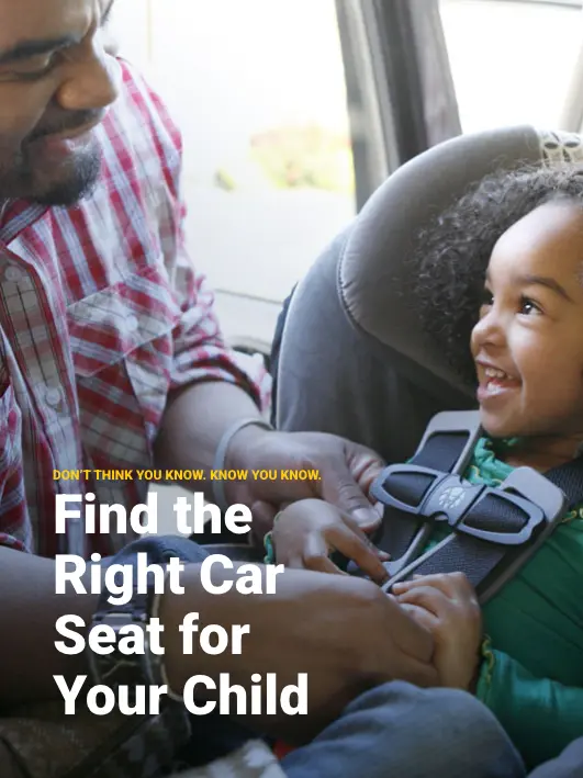 Father buckling smiling child into a car seat for safe travel — NHTSA car seat guide
