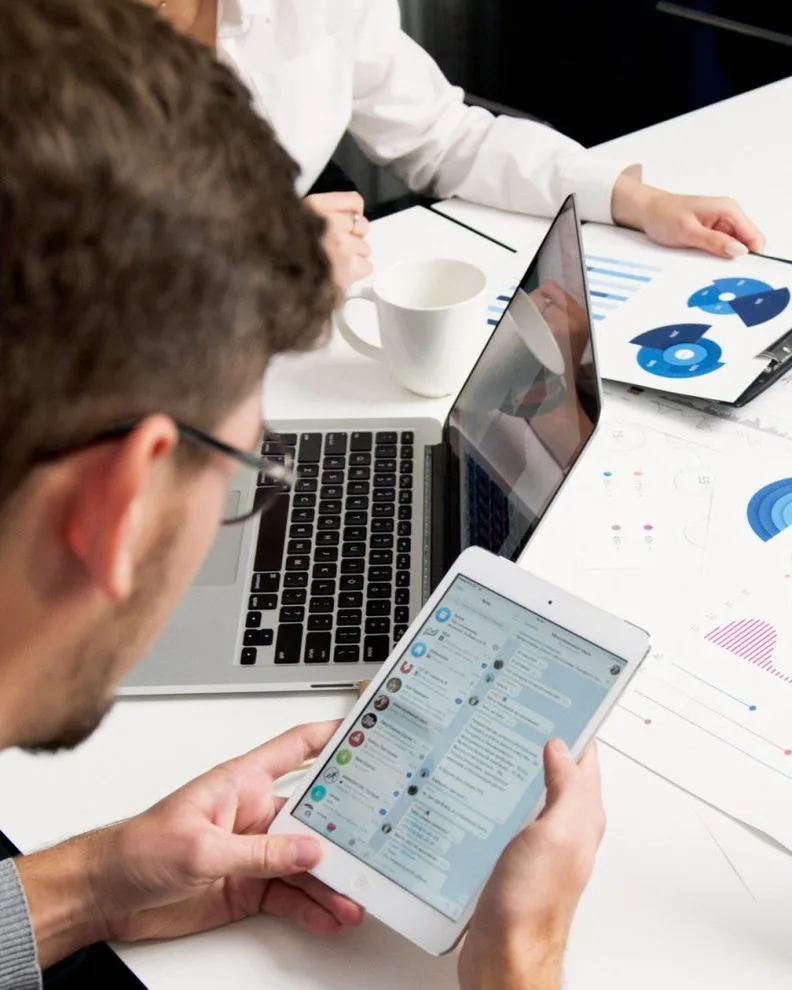 person viewing table of reports on google PPC campaign talking to coworker