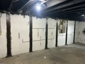 Interior basement wall with visible foundation repair, including epoxy injections and structural support beams, highlighting A-1 Basement Solutions' commitment to addressing structural integrity in homes.