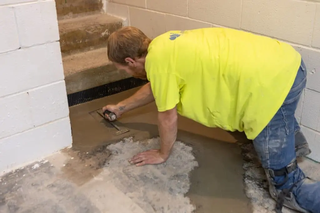 Worker applying concrete in a basement during waterproofing process, highlighting professional basement repair services.