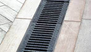 Floor drainage channel for basement waterproofing, designed to collect groundwater and direct it to a sump pump, surrounded by wooden flooring.