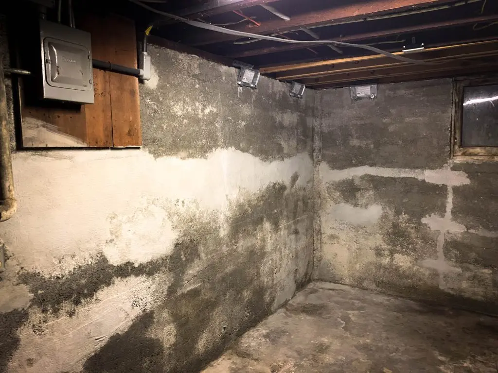 Basement interior showing potential water damage with exposed concrete walls and electrical panels, illustrating the need for professional basement waterproofing services.