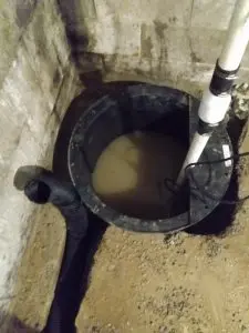 Sump pump in a basement with water, highlighting essential maintenance for preventing moisture-related issues during fall.