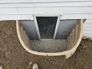 Egress window well with gravel drainage installed around basement window for proper water control