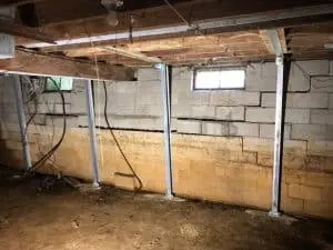 Basement interior with steel piers installed to stabilize bowing walls and prevent further structural damage, illustrating foundation repair techniques.