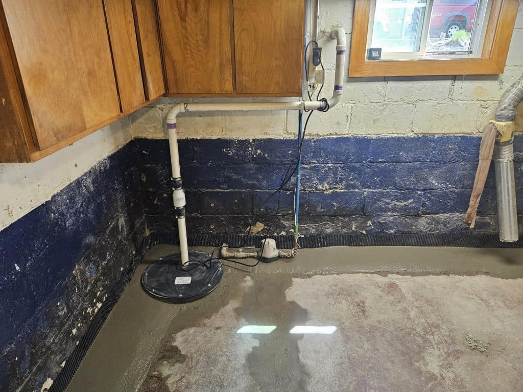 Sump pump installation in basement with waterproofing materials and plumbing, illustrating basement repair techniques.