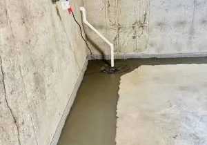 Interior basement waterproofing installation with a sump pump and drainage system on a concrete floor, illustrating effective moisture management techniques.