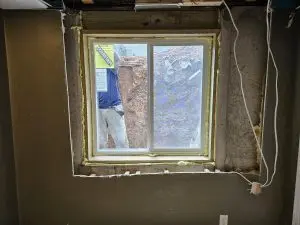 Basement egress window installation in Wisconsin with a new window framed into a concrete foundation wall