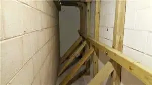 Interior view of a basement showing wooden bracing against foundation walls, illustrating foundation repair methods to prevent water intrusion and structural instability.