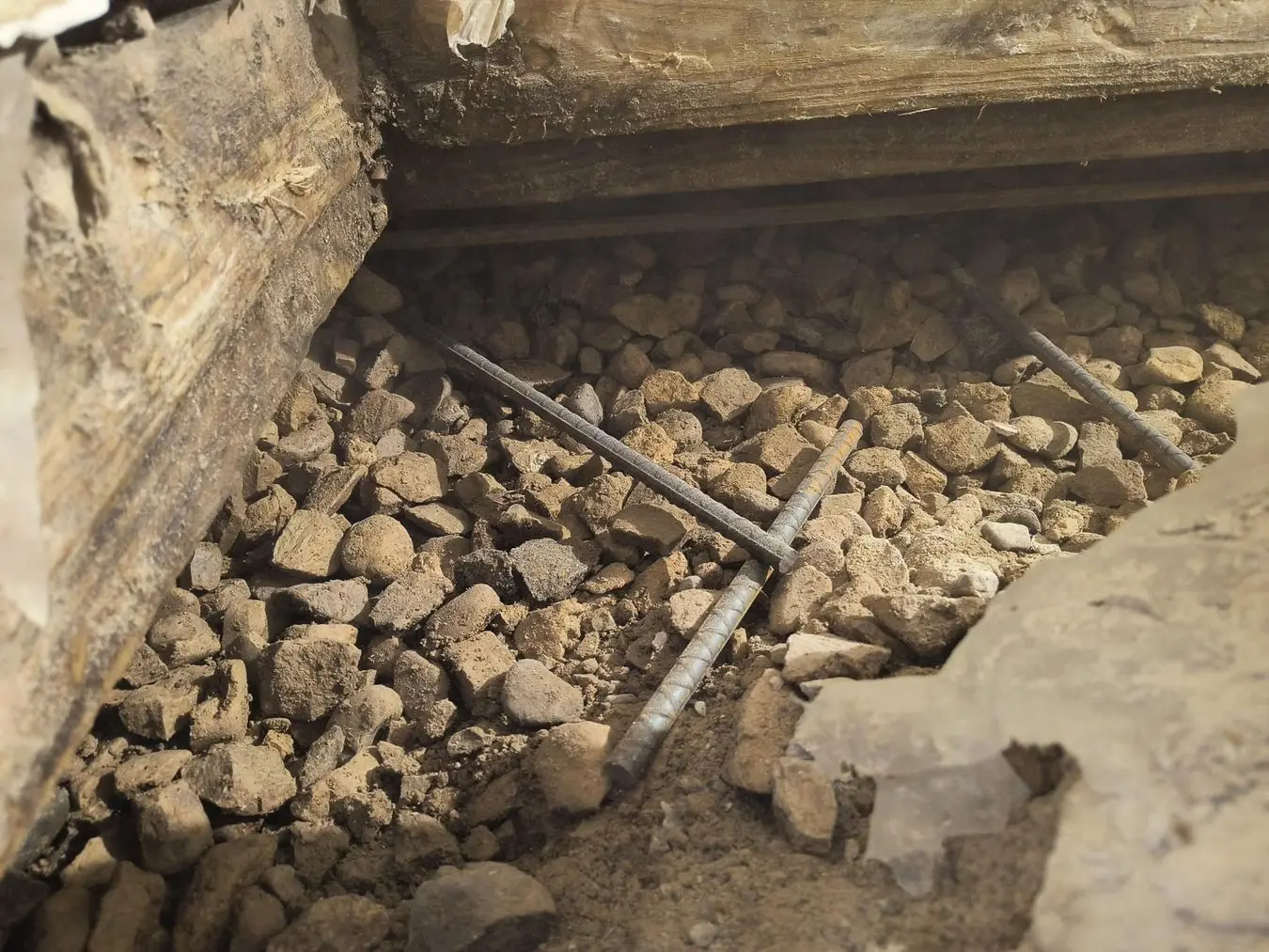Interior drainage system installation with gravel and rebar in a basement, illustrating effective water management for waterproofing solutions.