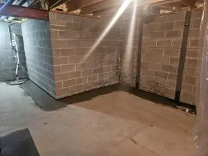 A well-lit basement with exposed brick walls, a concrete floor, sealed edges, and visible piping in the background. The space appears clean and organized.