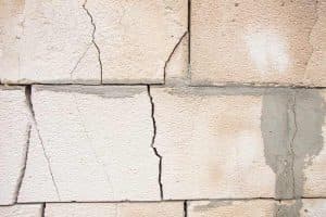 Cracked basement wall with visible damage and repair patches, illustrating common structural issues addressed by Basement Repair Specialists.