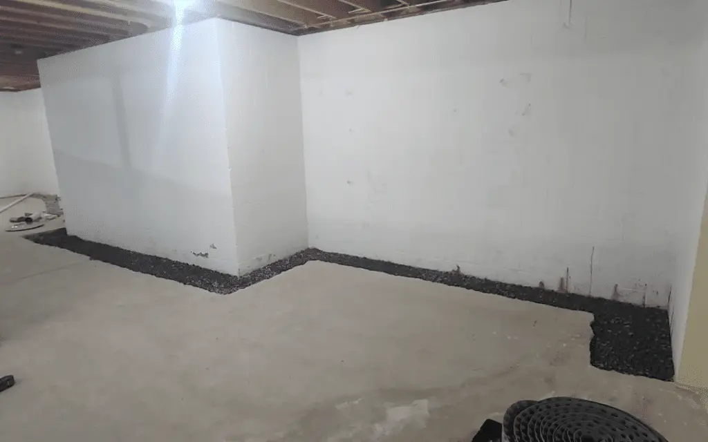Basement interior showing gravel perimeter and foundation wall, illustrating preparation for waterproofing and drainage solutions.