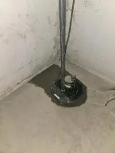 Sump pump installation in a basement, featuring a newly poured concrete base, emphasizing moisture control for a dry living space.