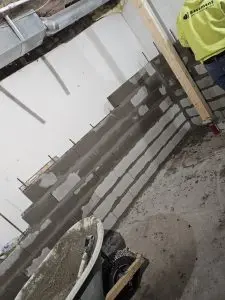 Basement wall under construction with masonry blocks, highlighting waterproofing preparations for enhanced property value and structural integrity.