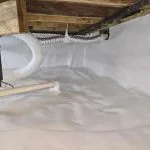 Encapsulated crawl space with white vapor barrier, drainage system, and sealed foundation for moisture control