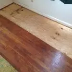 Sagging floor repair in Indianapolis showing repaired wood subfloor beside existing hardwood flooring