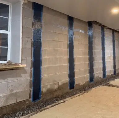 Carbon fiber reinforcement strips applied to a foundation wall, showcasing structural stabilization for residential applications.