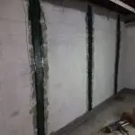 Carbon fiber reinforcement installed on a concrete wall, showcasing vertical strips enhancing structural integrity for foundation repair.