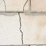 Close-up of a cracked wall surface, highlighting structural damage that may result from moisture infiltration or poor-quality materials, relevant to wall repair discussions.