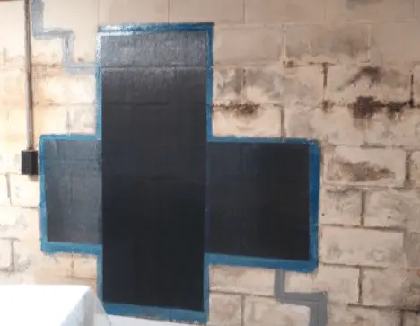 Carbon fiber reinforcement applied to a foundation wall with visible cracks, emphasizing structural repair techniques for basement stability.