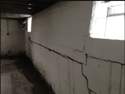 Crawlspace with visible cracks in the concrete walls and signs of moisture, emphasizing the need for professional waterproofing services and repair of butyl tape.