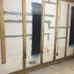 Basement wall with carbon fiber reinforcement installed for foundation repair, showcasing minimal disruption and eco-friendly construction methods.