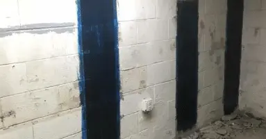 Interior basement walls with applied StablWall carbon fiber sheets for foundation reinforcement, showcasing the installation process and technology used to prevent wall movement.
