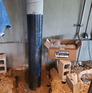 Foundation support column in basement with surrounding construction materials, illustrating foundation stabilization methods for homeowners.