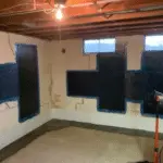 Basement interior showing foundation repair process with black sealant applied to wall cracks, emphasizing the importance of addressing foundation issues for home stability and health.