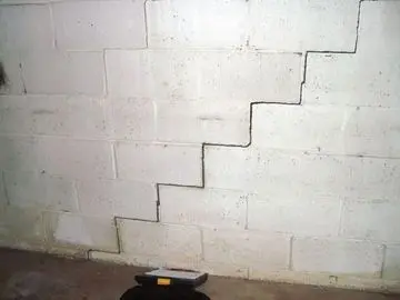 Cracked basement wall with visible separation in cinder block foundation, highlighting common foundation issues addressed by carbon fiber repair solutions.