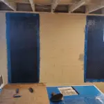 Wall with blue carbon fiber reinforcement applied, showcasing StablWall installation process for enhanced structural integrity and reduced maintenance costs.