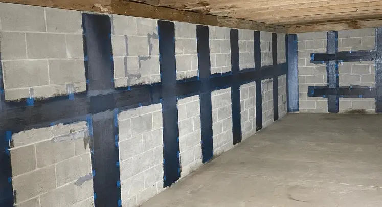 Interior view of a residential basement showing carbon-fiber structural reinforcement applied to concrete block walls, highlighting StablWall's innovative strengthening systems for foundation stabilization.
