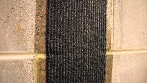 Carbon fiber reinforcement applied to a concrete wall, showcasing innovative foundation repair technology by StablWall for structural stability.
