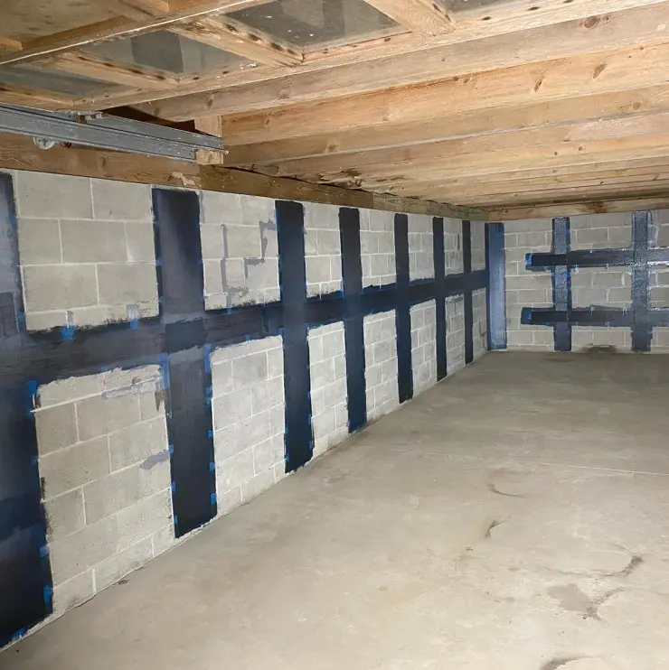 Carbon fiber strips applied to concrete walls in a basement, reinforcing structure for foundation repair, showcasing innovative home repair solutions.