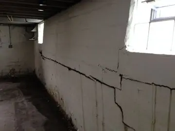 Basement wall with visible cracks and moisture damage, illustrating the need for carbon fiber reinforcement solutions for foundation stability.
