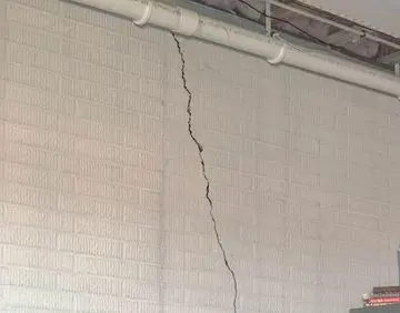 Cracked poured concrete basement wall highlighting potential foundation issues and the need for carbon fiber repair solutions.
