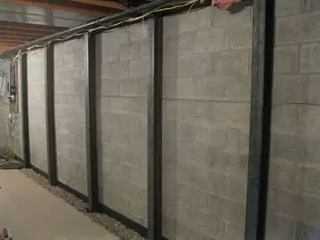 Carbon fiber reinforced foundation wall installation with visible steel supports, showcasing structural reinforcement for stability and durability in basement environments.