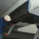 Worker applying carbon fiber reinforcement to a basement beam, showcasing foundation repair techniques for structural integrity and stability.
