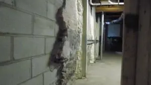 Basement hallway showing a significant horizontal crack in the foundation wall, indicating potential need for stabilization rather than simple crack repair.