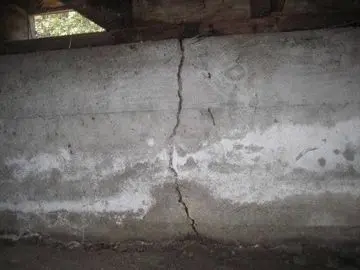 Cracked concrete foundation wall indicating potential structural issues related to moisture and foundation repair needs.