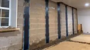 Carbon fiber reinforcement applied to basement wall for structural repair, showcasing innovative foundation stabilization technology.